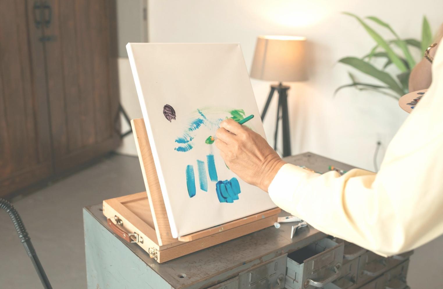 Aquarellmalerei mit verschiedenen Farbtönen und Pinseln auf einem Arbeitstisch